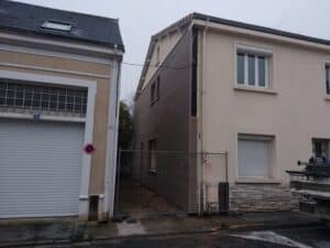 Maison en rénovation avec bardage bois brun, clôture de chantier et panneau d'interdiction au numéro 101.