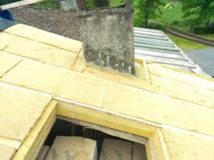 Panneaux d'isolation Steico en fibre de bois installés sur une charpente autour d'un conduit de cheminée.