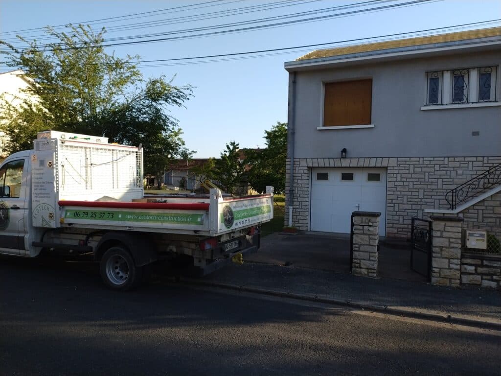 Camion Ecotech devant une maison grise. Services charpente, couverture. Tél: 06 79 25 57 73. www.ecotech-construction.fr