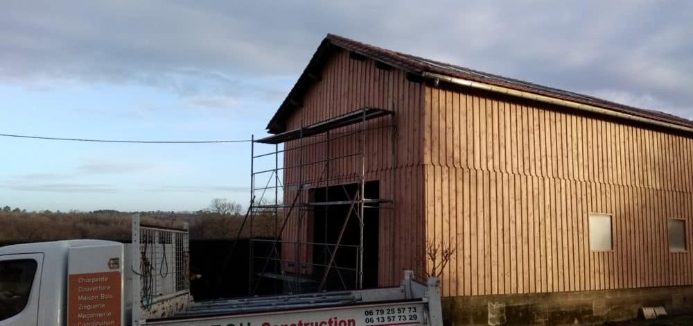 Rénovation de grange : bardage bois et charpente Bardage bois vertical sur grange avec échafaudage et camion de charpente TCH Construction.
